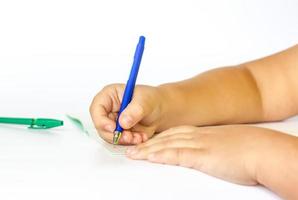 a criança mantém as mãos sobre um caderno aberto e vai escrever nele. close-up das mãos de uma criança. foto