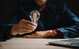 empresário tocando uma lâmpada brilhante. conceito de idéias para apresentar novas idéias grande inspiração e inovação novo começo. foto