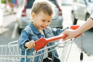 menino bonitinho sentado em um carrinho de compras foto