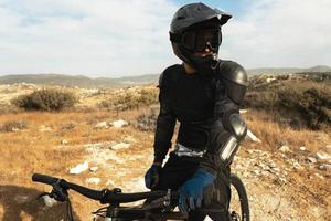 piloto de downhill totalmente equipado com equipamento de proteção andando de bicicleta foto