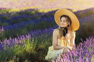 mulher jovem e bonita em um campo cheio de flores de lavanda foto