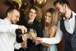 pessoas de festa bem vestidas comemorando feriado ou evento e bebendo vinho espumante foto