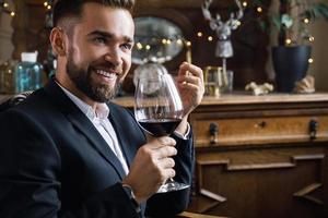 homem barbudo bonito com um copo de vinho tinto foto