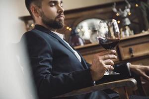 homem barbudo bonito com um copo de vinho tinto foto