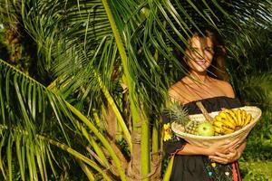 mulher jovem feliz com uma cesta cheia de frutas exóticas foto