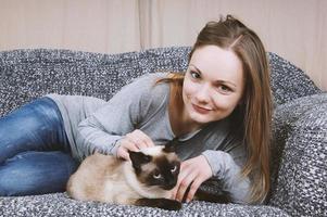 mulher jovem feliz relaxando no sofá com gato foto