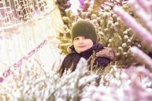 retrato de um menino à luz de luzes iridescentes. natal na cidade. close-up de decorações iluminadas. foto