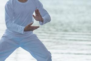 jovem praticando tai chi chuan tradicional, tai ji e qi gong no parque para o conceito saudável e tradicional de artes marciais chinesas em fundo natural. foto