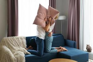 casal feliz durante luta de almofadas em seu apartamento foto