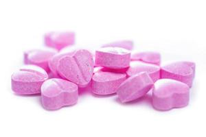 tiro de closeup de pílulas em forma de coração rosa no fundo branco. foto