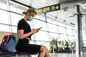 jovem usa máscara de prevenção em um aeroporto durante voo aguardando foto