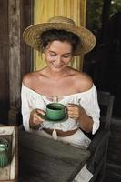 mulher feliz sentada no terraço de verão e tomando café foto