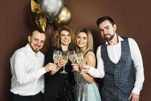 pessoas de festa bem vestidas comemorando feriado ou evento e bebendo vinho espumante foto