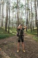 alpinista feminina está usando binóculos para observação de pássaros na floresta verde foto