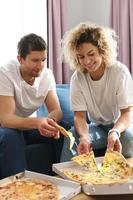 casal feliz comendo pizza deliciosa em casa foto