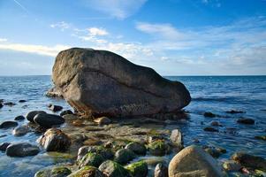 grande pedra na água na praia no mar. costa dinamarquesa em um dia ensolarado foto