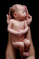 lindo bebê recém-nascido deitado nas mãos do pai foto