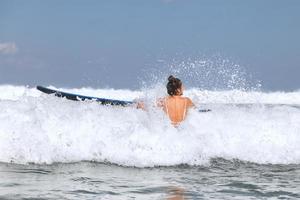 surfista mulher está tentando entrar em linha através de ondas durante seu treino de surf foto