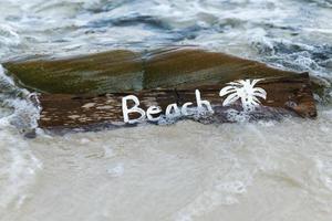 placa de madeira com letras na praia foto