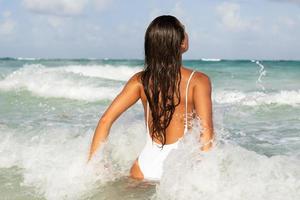 mulher vestindo maiô branco tomando banho no mar foto