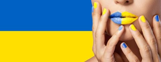 lábios femininos com batom amarelo e azul e bandeira ucraniana no fundo foto