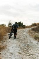 ciclista profissional em declive caminhando pela trilha da montanha foto