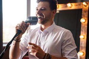 jovem sorridente com microfone está cantando em casa foto