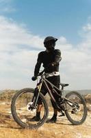 piloto de downhill totalmente equipado com equipamento de proteção e sua bicicleta foto