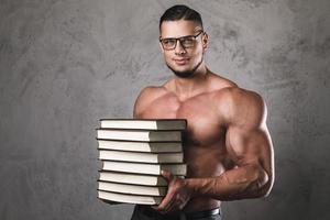 homem inteligente e musculoso com uma pilha de livros foto