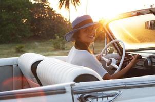 mulher jovem feliz e carro conversível retrô foto