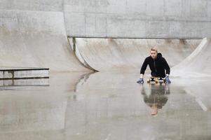 cara deficiente motivado com um longboard no skatepark foto