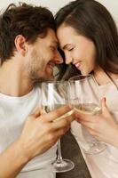 jovem casal bebendo vinho branco e relaxando em casa foto