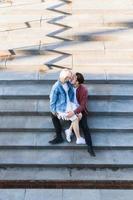 casal adolescente sentado e beijando em uma escada de concreto foto