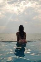 mulher sexy relaxante na piscina com borda infinita foto