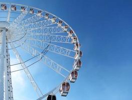 a metade da roda gigante em cracóvia contra um céu azul brilhante à luz do meio-dia. foto horizontal com lugar para texto.