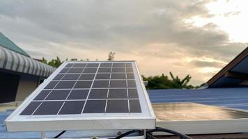 células solares do painel solar no telhado vermelho de uma casa e um lindo céu com fontes alternativas de energia do pôr do sol. o conceito de recursos sustentáveis foto