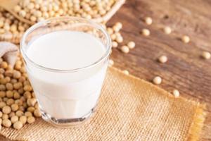 leite de soja em um copo com soja em uma mesa de madeira café da manhã orgânico, alta proteína, saudável, produtos agrícolas, vegetariano foto