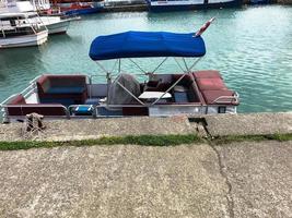 um pequeno barco com teto de lona esticada fica no cais do porto na água do mar foto