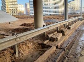 trabalho industrial de construção sob uma ponte com colunas e pára-choques e uma estrada de viaduto de carro grande foto