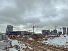 construção de casas, um shopping center de blocos de concreto na cidade. construção de um novo bairro residencial no inverno. guindastes e equipamentos de construção erguem um quarto foto