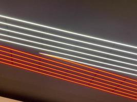 textura de neon brilhante vermelho e branco brilhante levou listras abstratas de laser multicoloridas e linhas de lâmpadas paralelas. o fundo foto