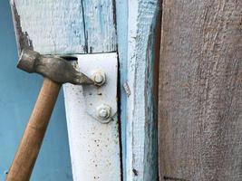 martelo em um cabo de madeira com ponta de metal. martelar pregos em uma superfície de metal. folha de metal é pintada de cinza. construindo uma casa, móveis para toda a vida com suas próprias mãos foto