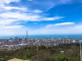 a vista do alto de uma bela cidade turística com prédios e casas, telhados de árvores e plantas, natureza contra um céu azul e montanhas. arquitetura antiga europeia foto