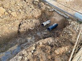 um poço escavado é uma vala para a colocação de cabos e fios com canos sob o solo durante a construção e reparo de casas na cidade da megalópole foto