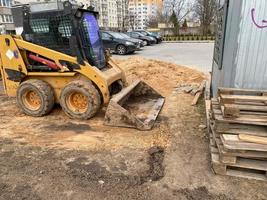 mini escavadeira cavando terra em um campo ou floresta. colocando canos de esgoto subterrâneos durante a construção de uma casa. cavar trincheiras para um gasoduto ou oleoduto. terraplenagem, poço de fundação foto