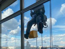 fora do prédio lavando o vidro da fachada de um prédio de vários andares alpinistas limpam janelas foto