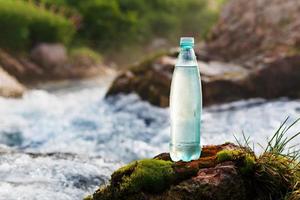garrafa de plástico com água potável no fundo de um riacho de montanha, na natureza. ool água doce foto