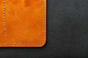 bolsa marrom, carteira feita de nobuck de couro genuíno em um fundo escuro. elementos de produtos artesanais de couro feitos à mão foto