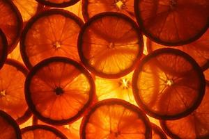 fatias suculentas de laranja madura com luz de fundo na forma de anéis cortados, fundo-substrato textural foto