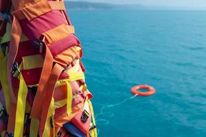 a bóia salva-vidas de cor laranja é jogada no mar azul contra o fundo do salva-vidas foto